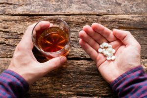 Man holding liquoe glass and pills